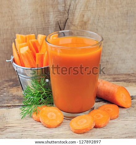 Carrot Juice And Carrot Segments On A Wooden Background