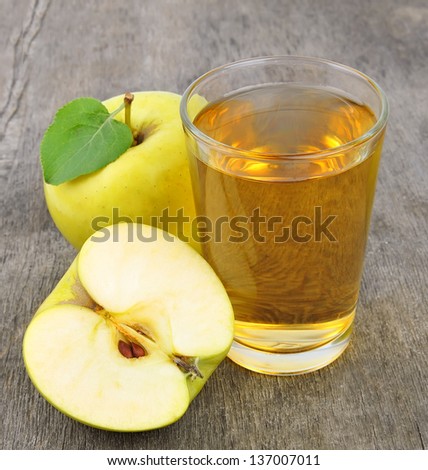 Apple juice and yellow apple close up on wooden tables