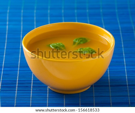 soup in yellow bowl on the blue pad - stock photo