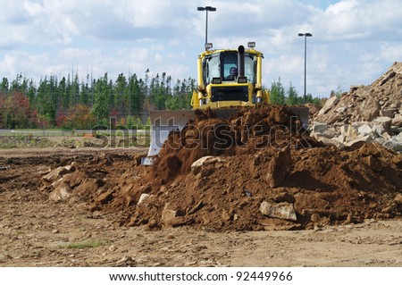 A bulldozer moving earth to level a pile of earth