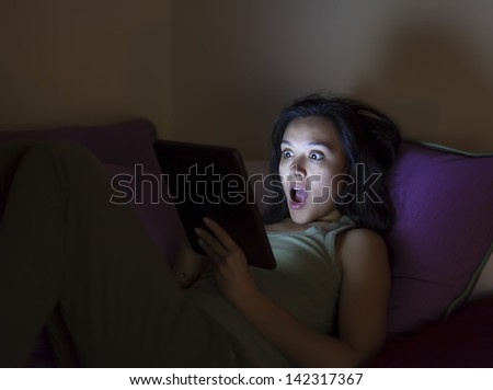 Young woman reading a tablet in the dark