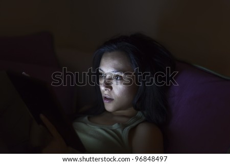 Young woman reading a tablet in the dark