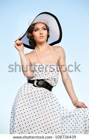 Portrait of pretty woman wearing white dress and straw hat in sunny warm weather day.  Walking at summer park.
