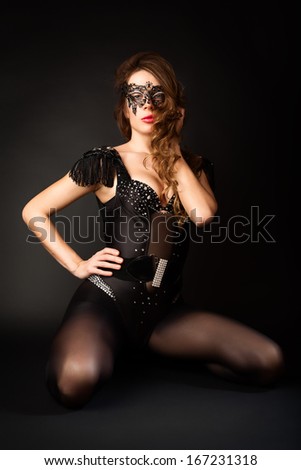 Beautiful girl in the masquerade mask on a black background. Portrait of sexy woman with black party mask on face.