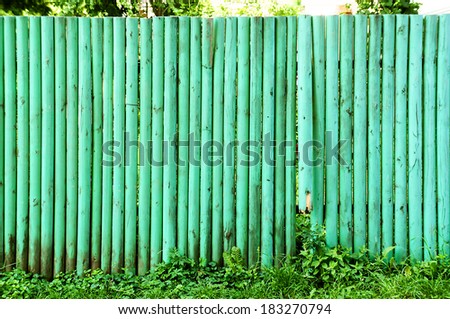 Wooden fence green background. One wooden boards broken.