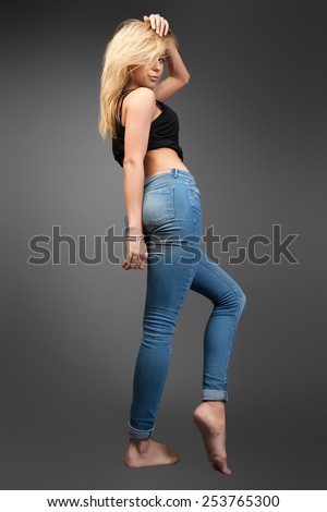 Modern hip-hop dance girl shows off her belly. Young go-go dance girl isolated on black background.