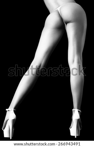 Legs with white high-heeled shoes on a black background. Black and white style photo.
