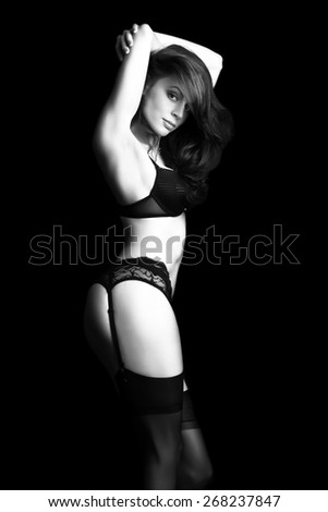 Portrait of a beautiful fashion model in stylish underwear posing over dark black background. Vogue style. Black and white studio shot