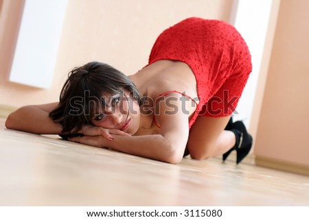 Beautiful woman in a red dress on wood floor.