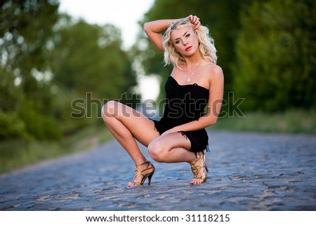 The woman squats on paved road.