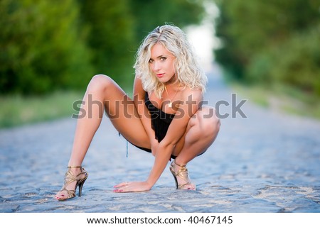 The woman squats on paved road.
