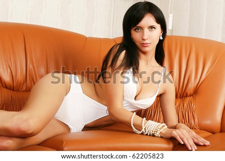 Glamour model poses on the leather sofa.