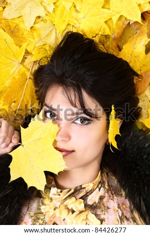 Portrait woman in fur collar. Autumn yellow leaves are on the background.
