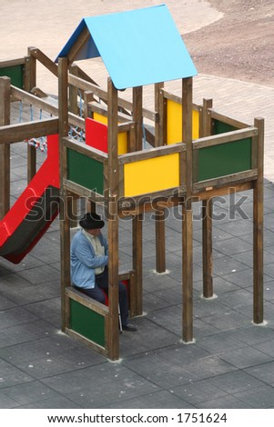 Old man sheltering from the midday sun under a children\'s climbing apparatus
