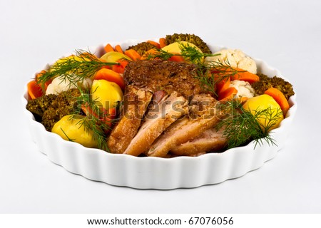 Slices of meat on a round plate with vegetables