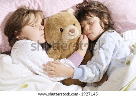 two little girls sleeping with a plush bear