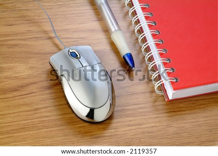 a silver mouse near a pencil and a note pad