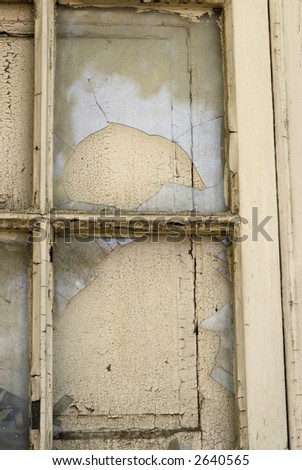 close up and detail of rustic window, with broken glass, old painting and closed blind