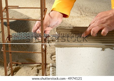 worker hands while aligning a metal plate over a concrete block