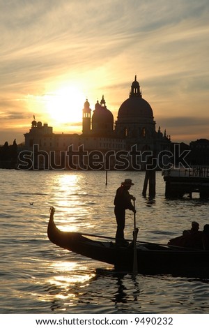 Whilst the sun falls behind the Church of Madonna Della Salute in Dorsoduro , Venice , a gondolier passes left to right in the foreground.