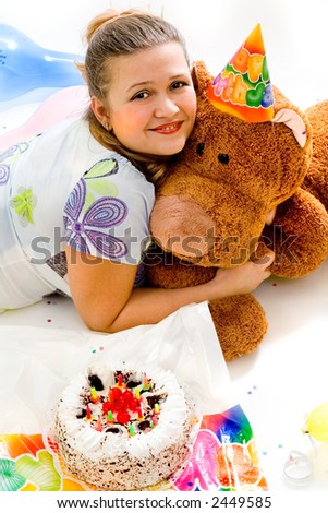 Girl and teddy bear are celebrating birthday with creamy cake