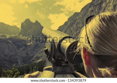 Woman in the mountains looks through telescope