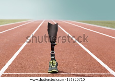 Athletic sports prosthesis of a disabled athlete stands on a tartan track