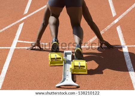 Dark-skinned sprinter in start position prepares for the start