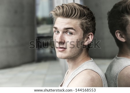 Young man leans against window of modern building
