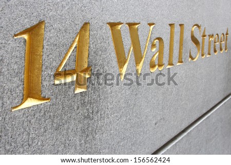 Wall street address  in golden letters embedded  on rough granite wall