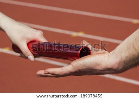 Female athlete hands over the relay race bar to a male athlete