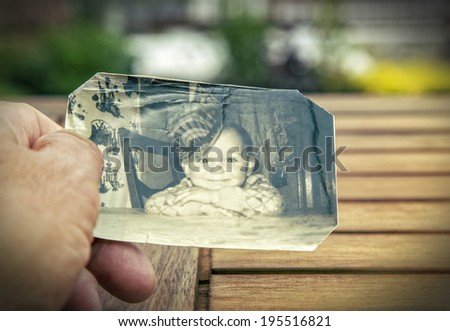 Man holds a  childhood picture of the sixties in his hand.