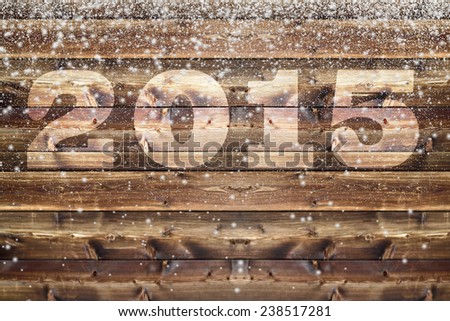 Wooden board with bleached out 2015 letter and falling down fluffy snow flakes of different size