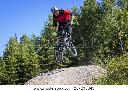 Mountain bike rider jumps over a dirt track kicker