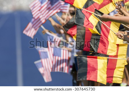 Spectators waving with flags of Germany and USA in front of a blue tartan track. Focus is on the german flags in the foreground