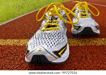 Pair of sports shoes standing on a tartan race track