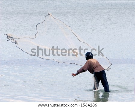 Lonely fishing man in southern Thailand throwing his fishing net and wearing a helmet for protection due to the fishing method