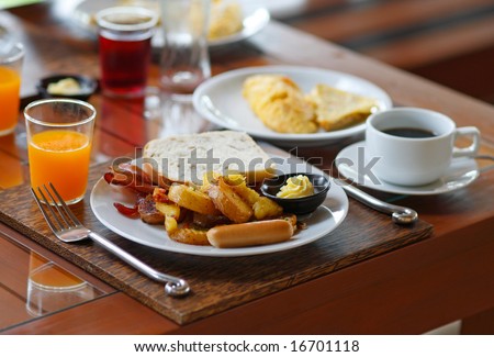 American Breakfast set with omelet, bacon, sausages, bread, potatoes, orange juice and a cup of coffee