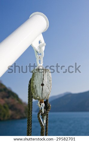 Old wooden block and ropes on a ship deck against blue sky