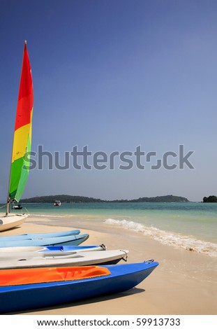 Colorful sailboat and some rental kayaks along an exotic beach in southern Thailand