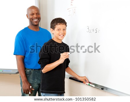 African American teacher and student doing simple algebra equation at the blackboard.