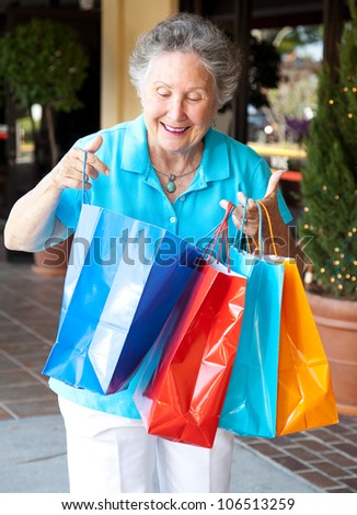 Senior woman smiles as she looks into her shopping bags to check out what she\'s bought.