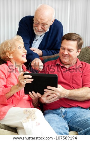 Senior couple learns how to use their new tablet PC from their adult son.