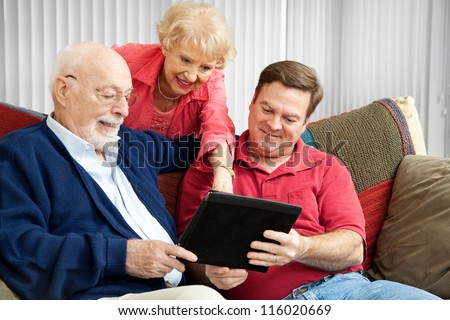 Adult son and elderly parents using their tablet PC at home.