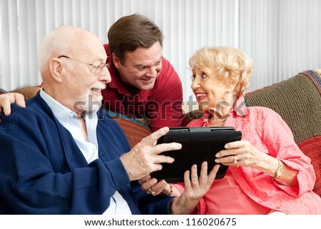 Senior couple get a gift of a tablet PC from their adult son.