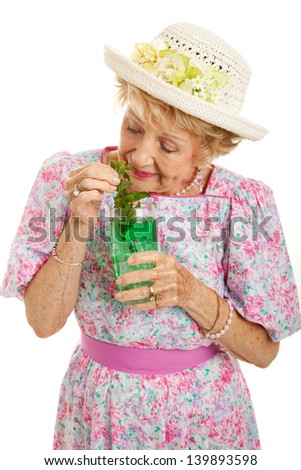 Senior lady getting a little bit drunk on a mint julep cocktail.  Isolated on white.