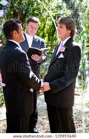 Handsome gay couple getting married outdoors in the park.