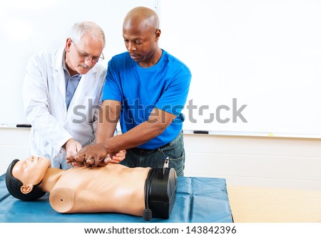 Doctor teaching first aid CPR techniques to an adult, African-american student.  Room for text.