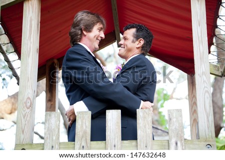 Happy gay couple getting married on the playground of a park.