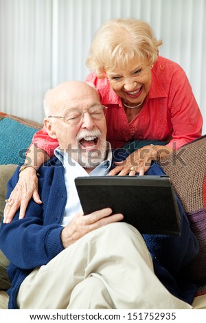 Senior Couple Having Fun And Laughing While Using Their Tablet Pc Computer.